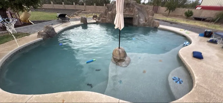 Hazy pool water with floating debris in a Queen Creek, Arizona pool with rock waterfall