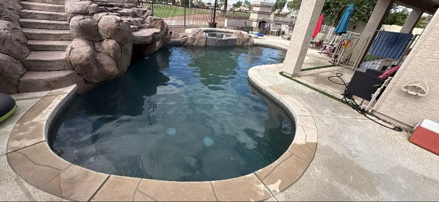 Murky, slightly dark pool water in a Queen Creek, Arizona backyard pool with raised spa