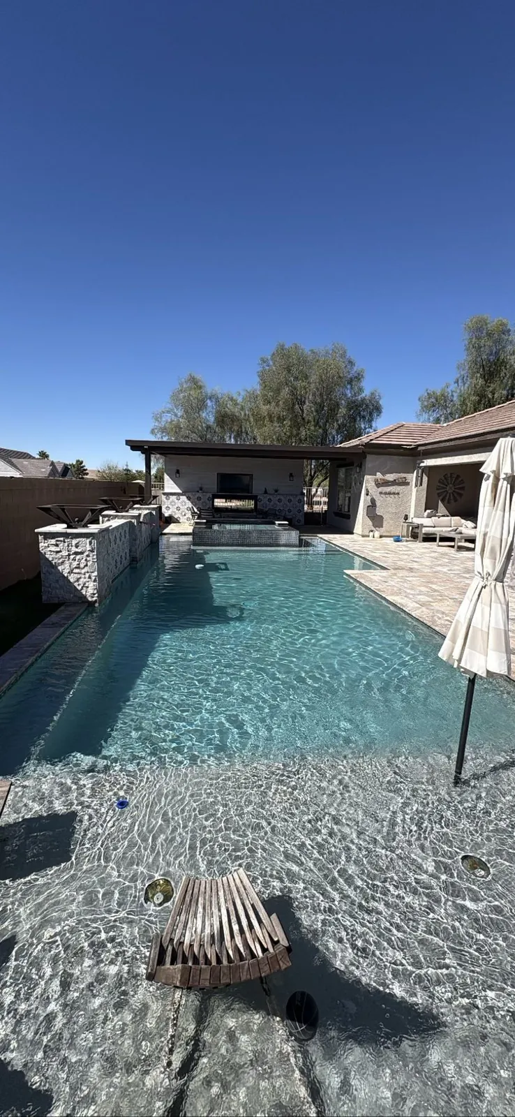 Raised spa and spillway wall beside a lap pool and outdoor kitchen in Queen Creek, Arizona