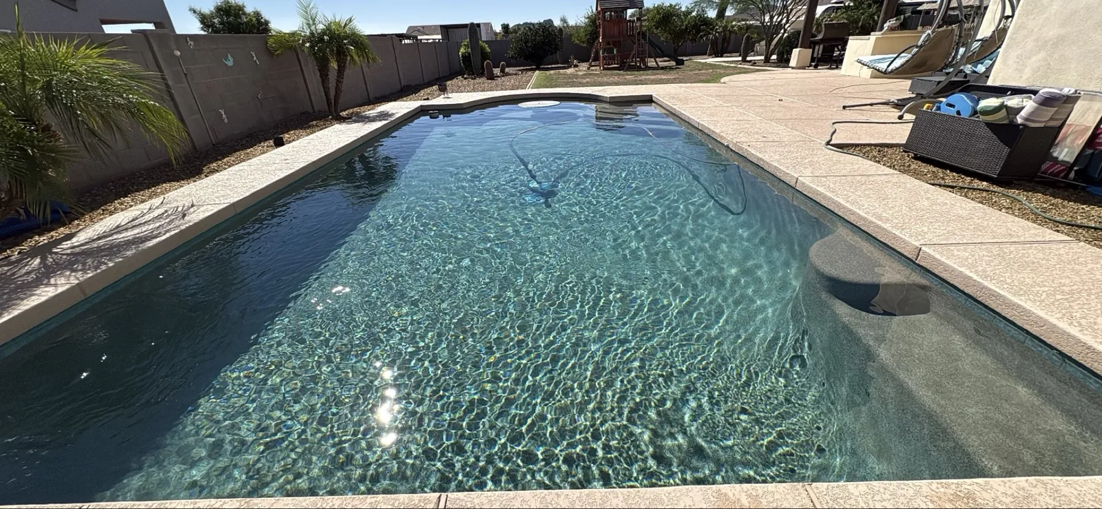 San Tan Valley backyard pool with tanning shelf being vacuumed during a weekly service visit