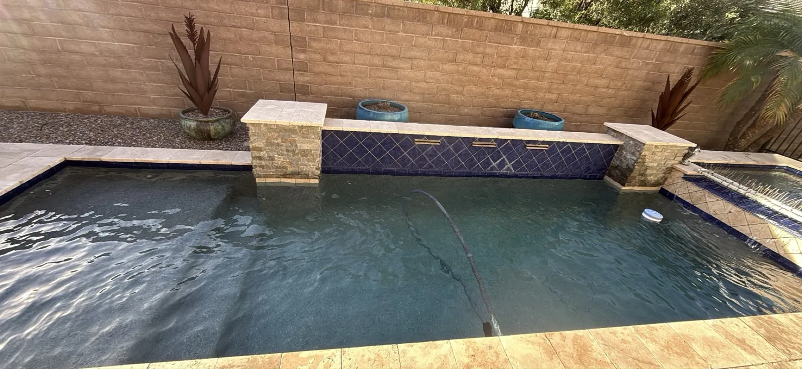 San Tan Valley pool with slightly cloudy water and a service hose during a maintenance stop