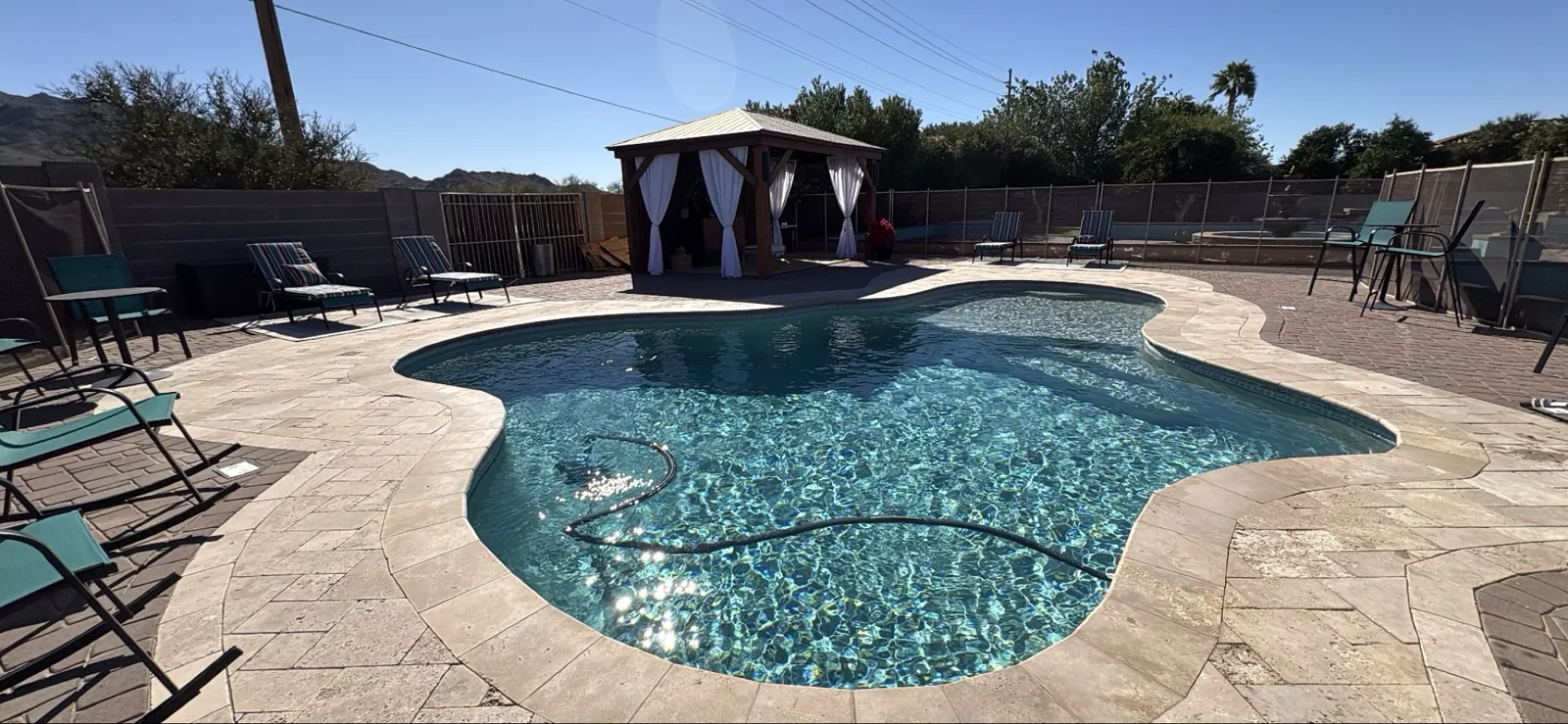 Vacuum hose in a Queen Creek pool and spa with gazebo and mountain backdrop